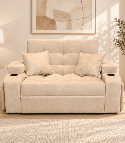 Sofá cama beige con dos cojines y portavasos en un living luminoso